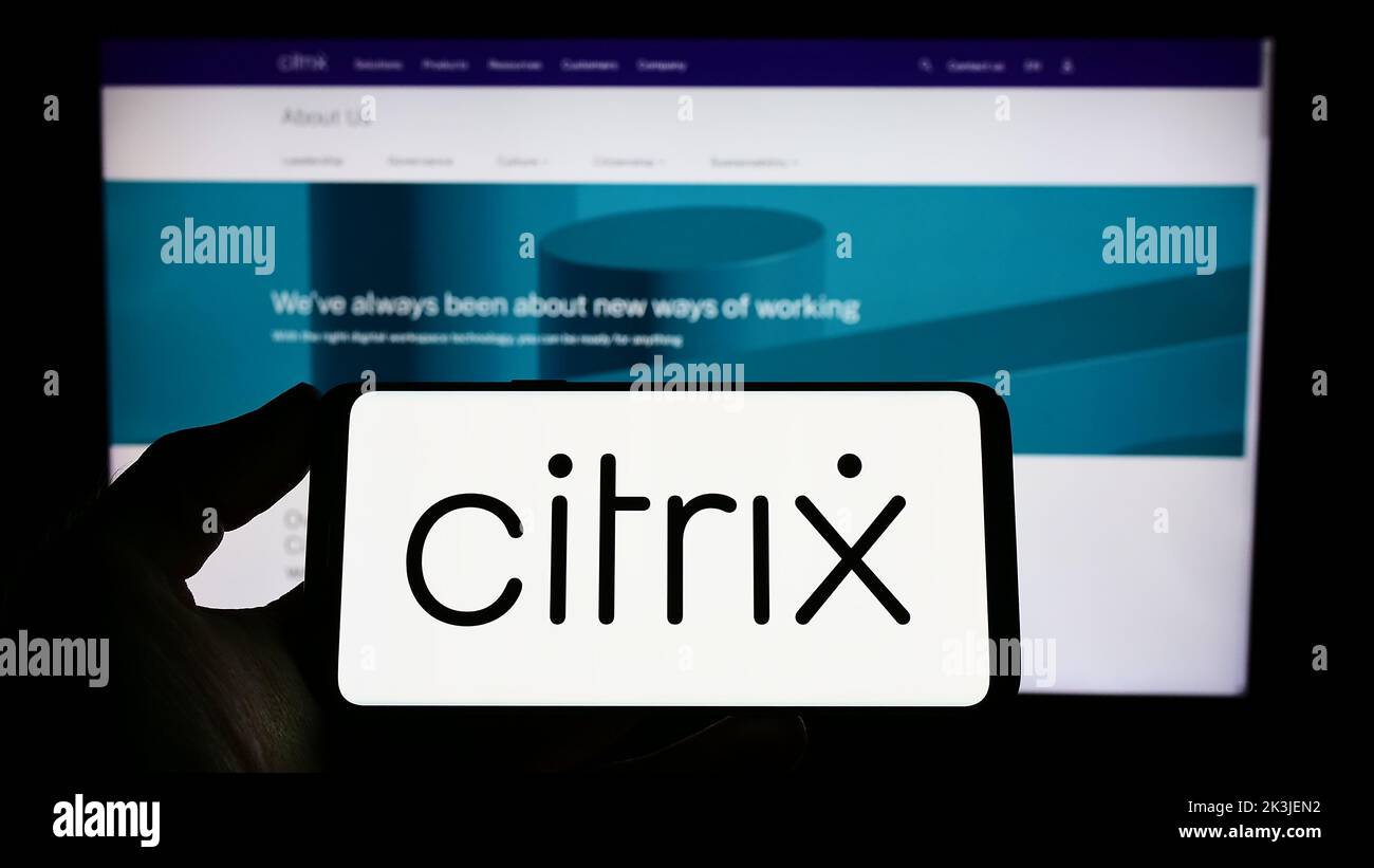 Personne tenant un téléphone portable portant le logo de la société américaine de cloud computing Citrix Systems Inc. À l'écran devant la page Web. Mise au point sur l'affichage du téléphone. Banque D'Images