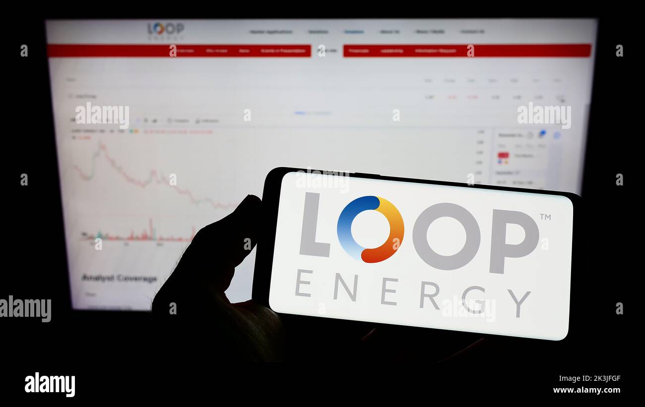Personne qui tient un téléphone portable avec le logo de la société canadienne d'hydrogène Loop Energy Inc. À l'écran devant la page Web. Mise au point sur l'affichage du téléphone. Banque D'Images