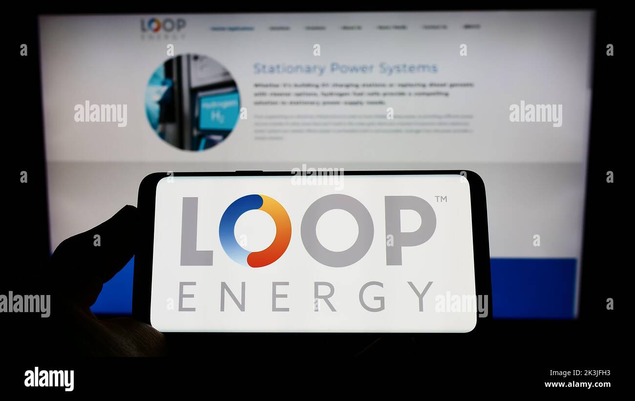Personne tenant un téléphone cellulaire avec le logo de la société canadienne d'hydrogène Loop Energy Inc. À l'écran devant la page Web des affaires. Mise au point sur l'affichage du téléphone. Banque D'Images