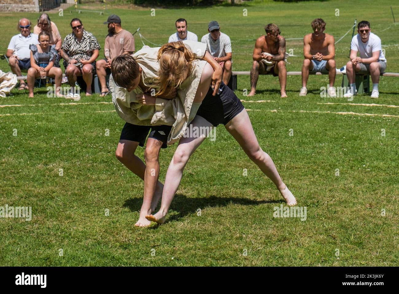 Une jeune adolescente lutte avec un garçon en compétition dans le Grand Tournoi de Wrestling Cornish sur le pittoresque village vert de St Mawgan à Pydar i. Banque D'Images