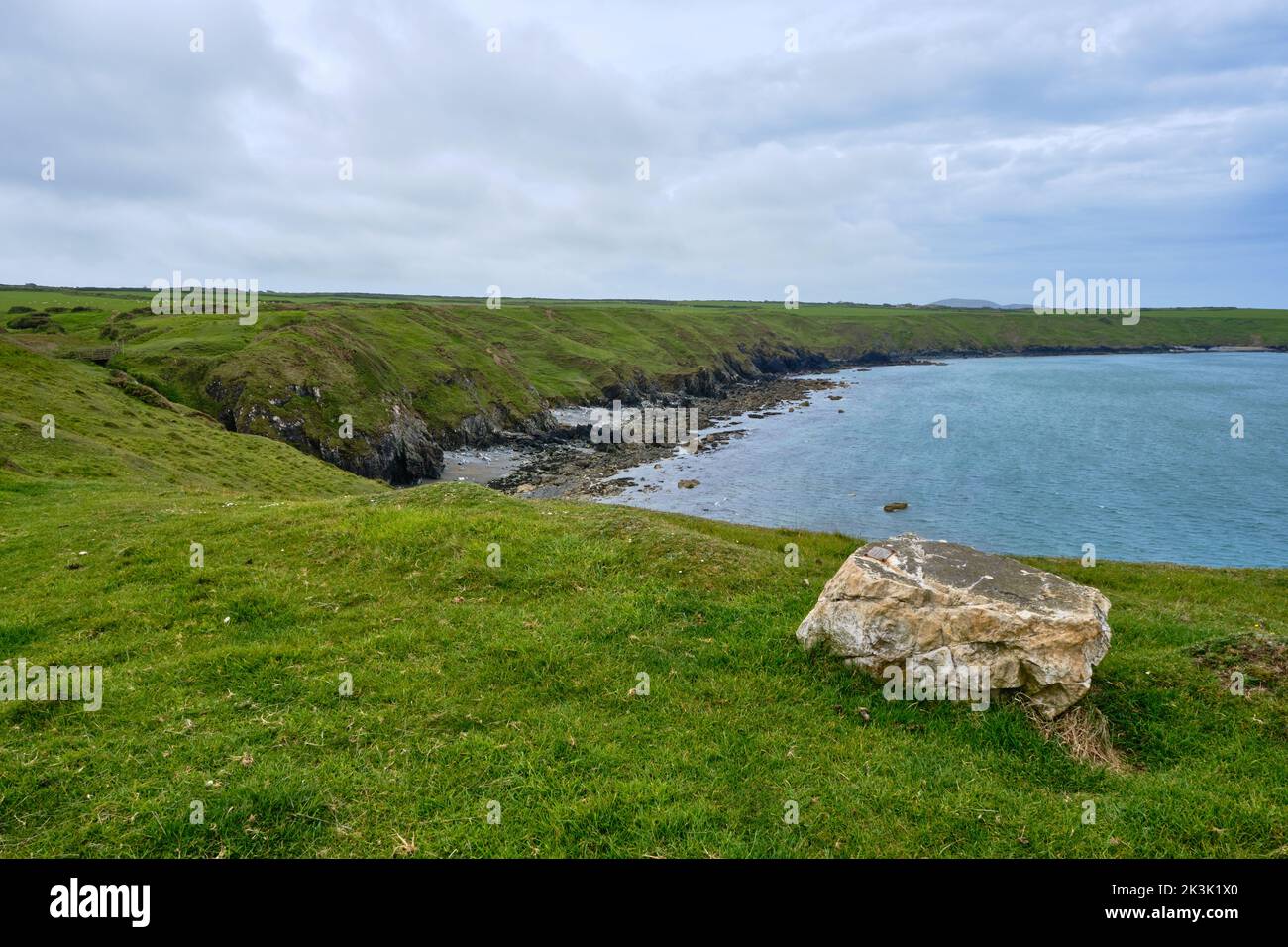 Un rocher offre un siège naturel pour admirer la côte de la péninsule de Llyn le long du Wales Coast Path Banque D'Images