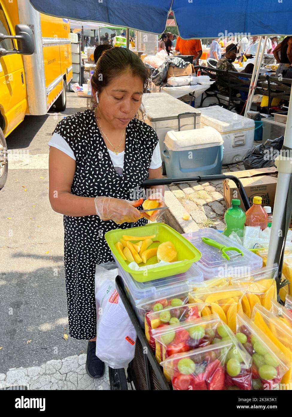 Woman fabrique des tranches de mangue à vendre avec d'autres fruits frais le long de Eastern Parkway lors de la West Indian Day Parade annuelle de la fête du travail à Brooklyn, New York. Banque D'Images
