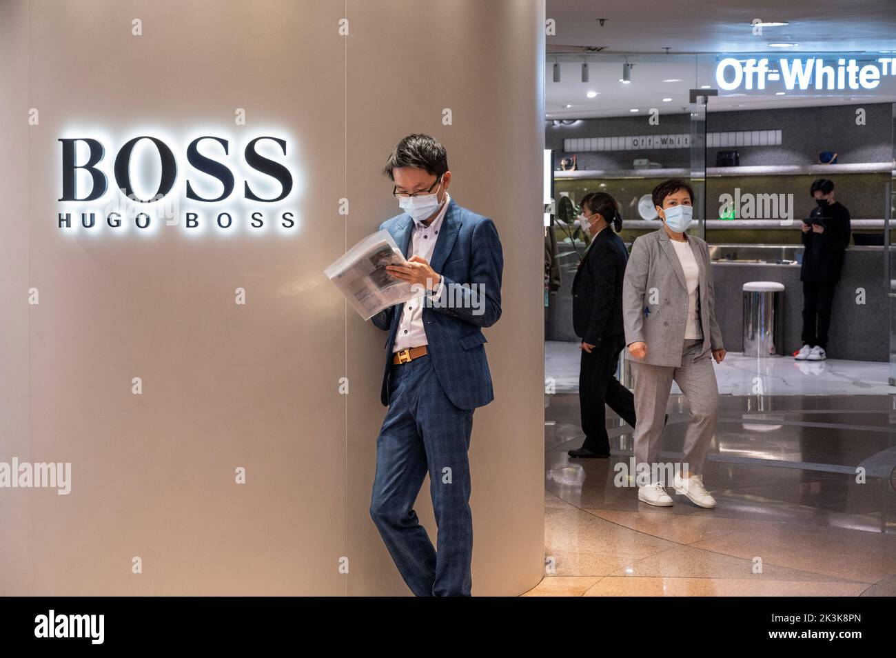 Un homme portant un costume est vu lire à l'extérieur de la marque de vêtements allemande Hugo Boss magasin à Hong Kong. Banque D'Images