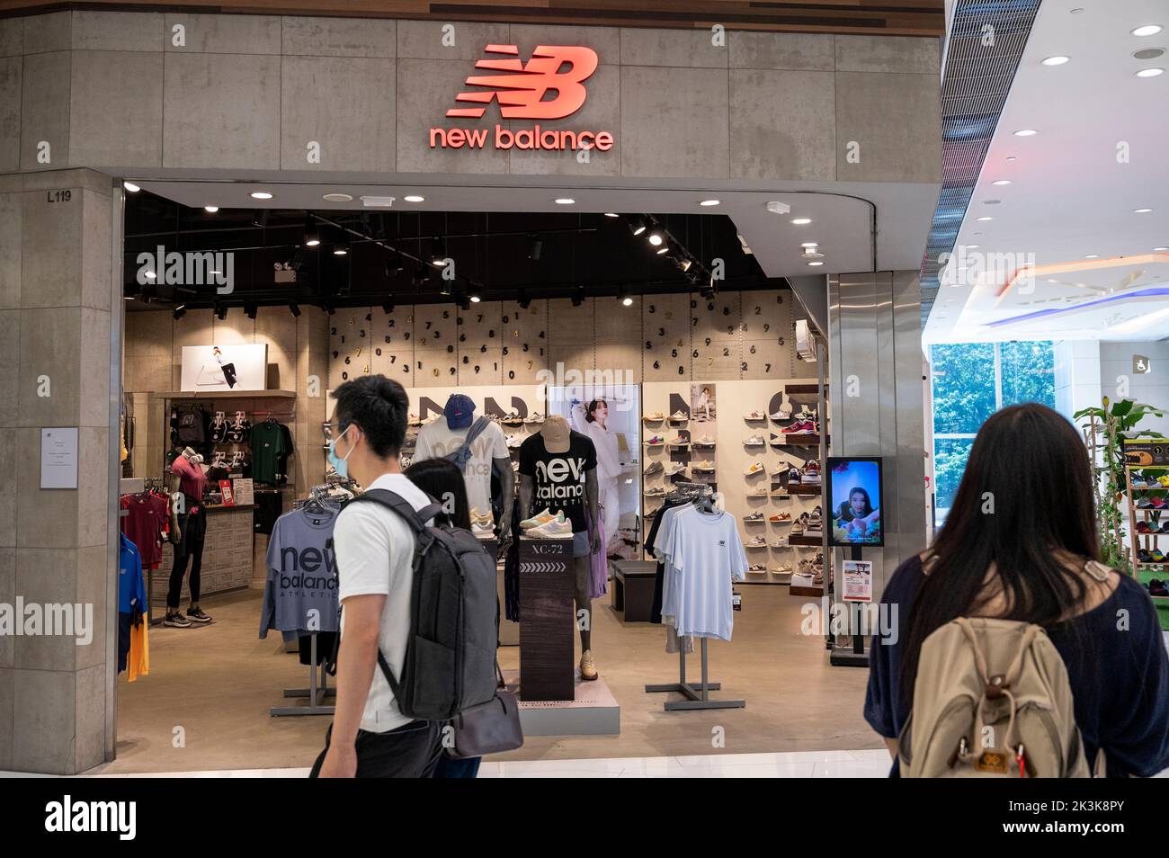 Les acheteurs se prominent devant le magasin et le logo New Balance (NB) de la marque américaine de chaussures à Hong Kong. Banque D'Images