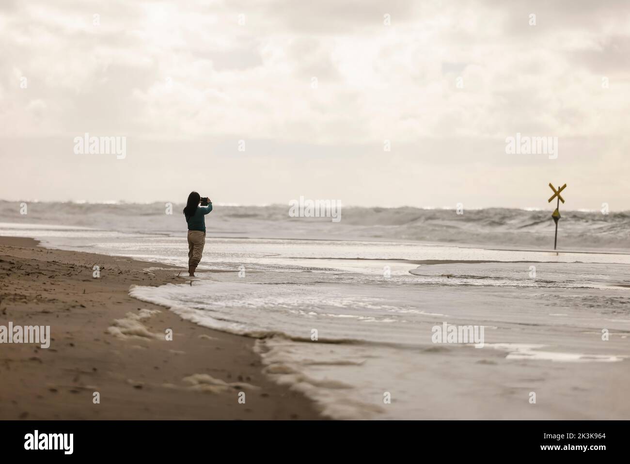 27 septembre 2022, Schleswig-Holstein, Westerland/Sylt: Un marcheur prend une photo sur la plage de Brandebourg lors d'une pause en compétition à la coupe du monde de Windsurf. Photo: Frank Molter/dpa Banque D'Images