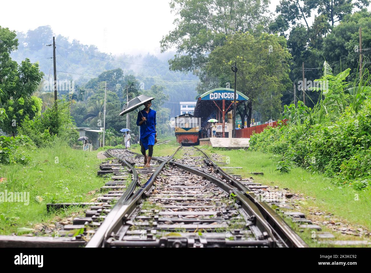 Homme marchant sur le chemin de fer un jour de pluie. Il a un parapluie dans sa main. Homme avec un parapluie sur le chemin de fer, attendant de nouvelles aventures et Voyage. Banque D'Images