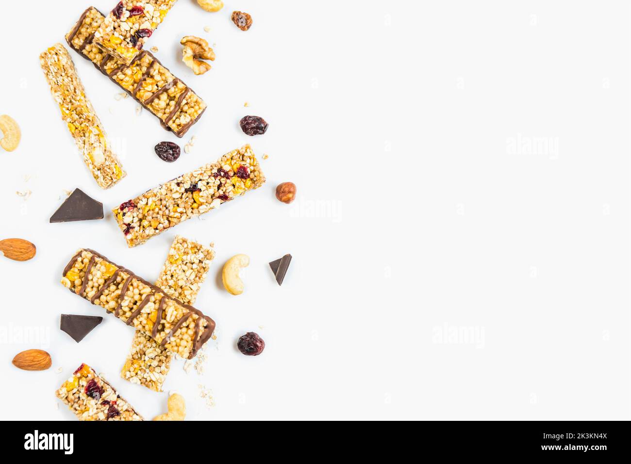 Vue de dessus de diverses barres de granola maison avec des noix, des graines, du chocolat noir, du miel et des baies sur un fond blanc. Copier l'espace Banque D'Images