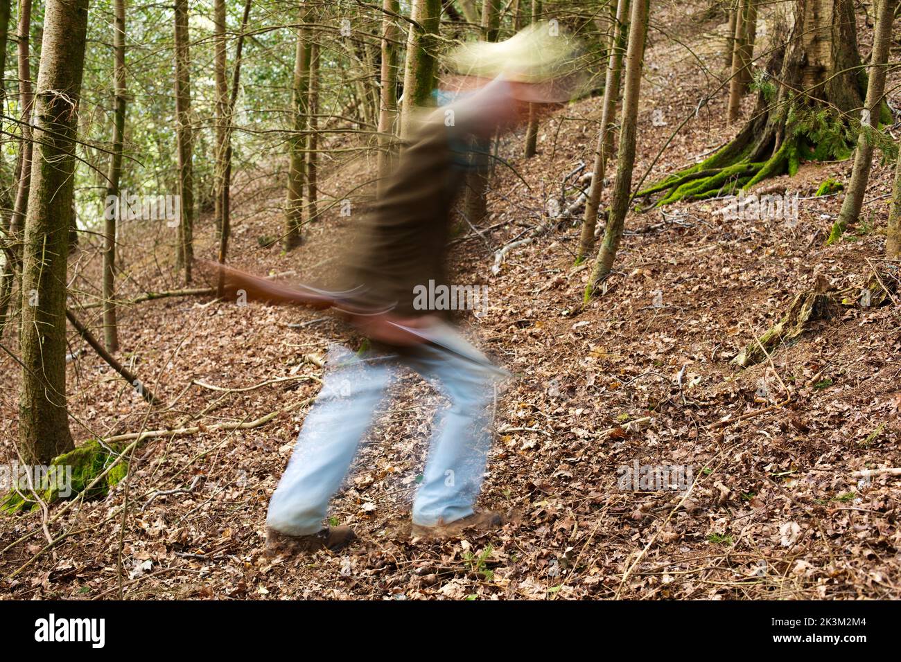 Une image de blury d'un homme qui marche à travers les bois a un fusil Banque D'Images