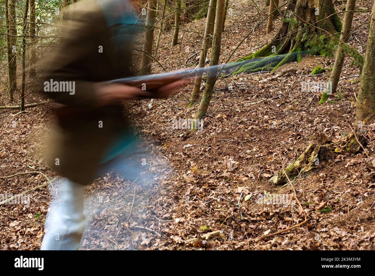 Une image de blury d'un homme qui marche à travers les bois a un fusil Banque D'Images