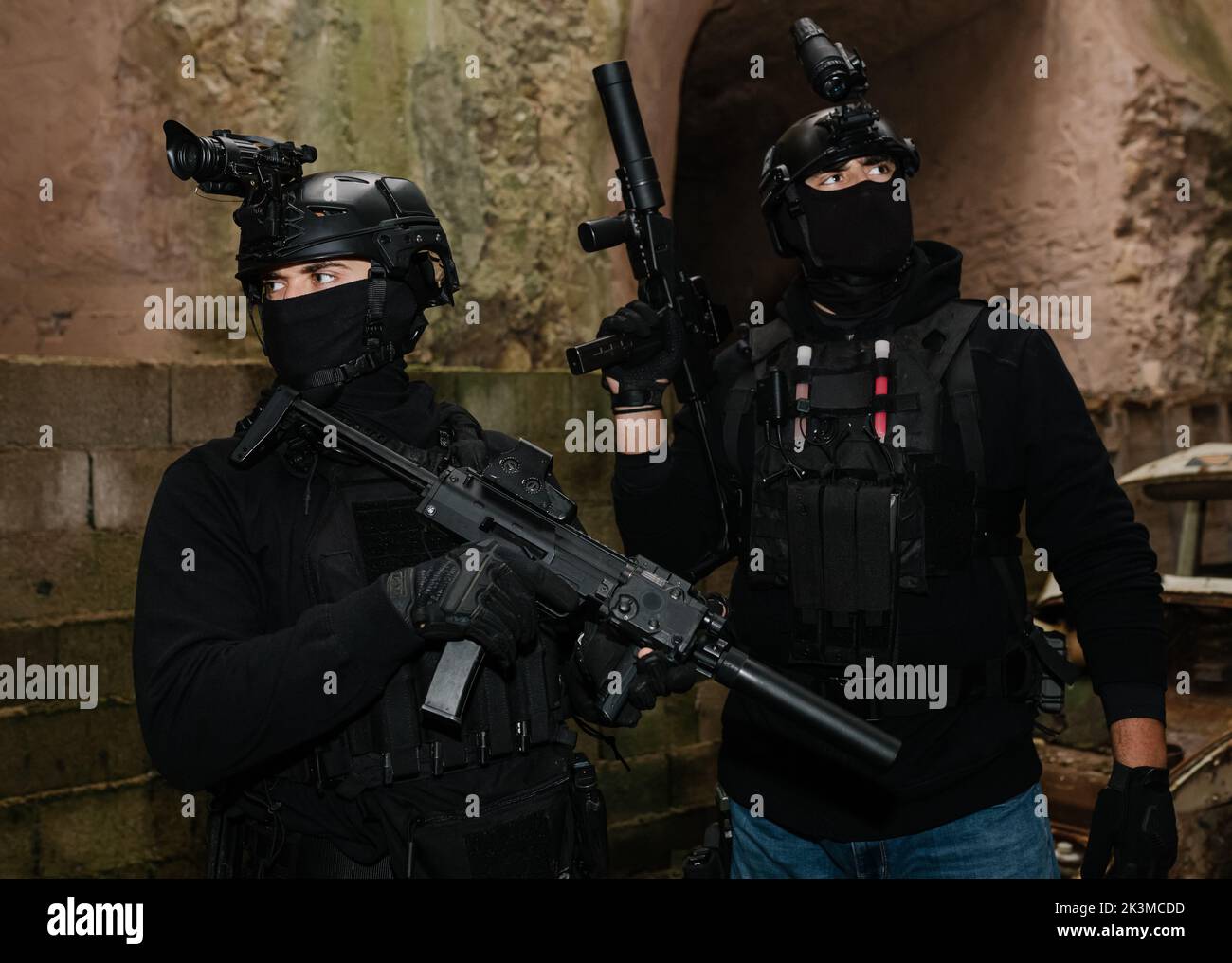Corps complet de combattants des forces spéciales non reconnaissables en équipement de combat et casques de protection visant avec des fusils modernes près des murs du vieux bâtiment Banque D'Images