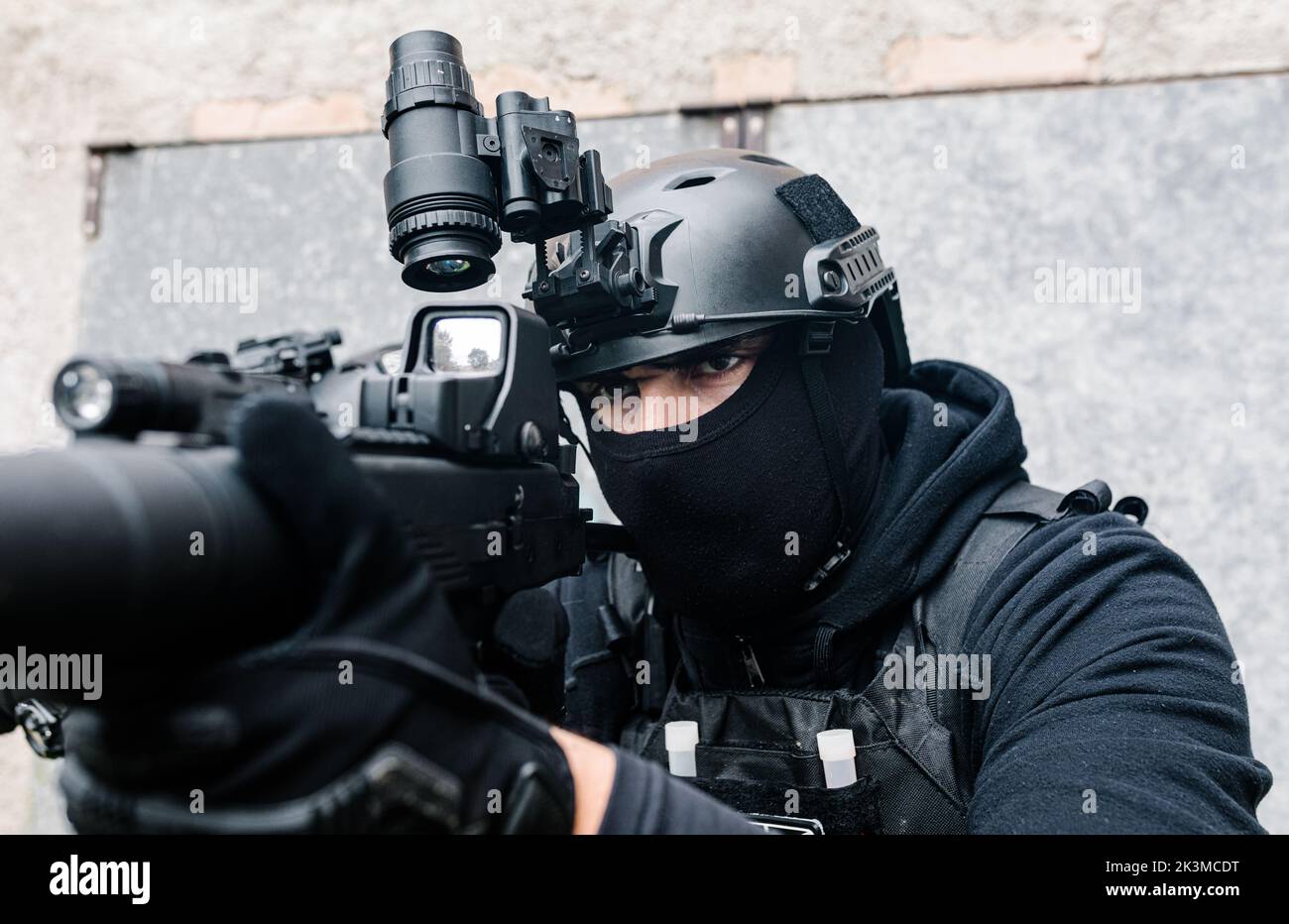 Corps complet de combattants des forces spéciales non reconnaissables en équipement de combat et casques de protection visant avec des fusils modernes près des murs du vieux bâtiment Banque D'Images