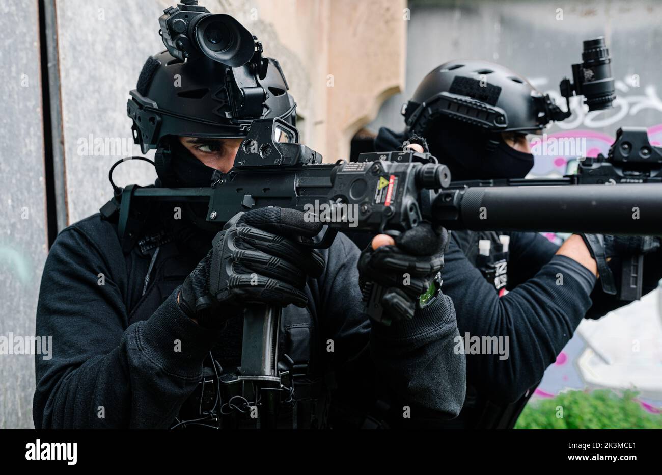 Corps complet de combattants des forces spéciales non reconnaissables en équipement de combat et casques de protection visant avec des fusils modernes près des murs du vieux bâtiment Banque D'Images