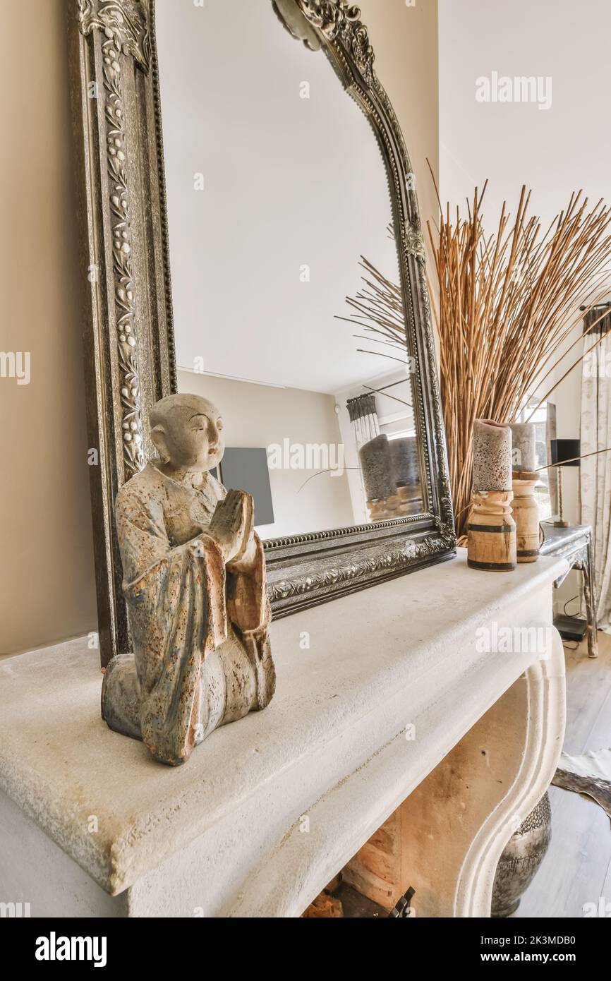 Décoration d'une figure de moine de prière à côté d'un miroir dans une maison moderne avec cheminée Banque D'Images