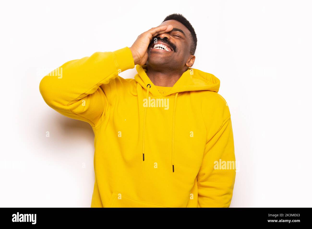 Joyeux homme americain d Afrique en pull a capuche jaune regardant l appareil photo et touchant le front tout en se tenant contre un fond blanc Photo Stock Alamy