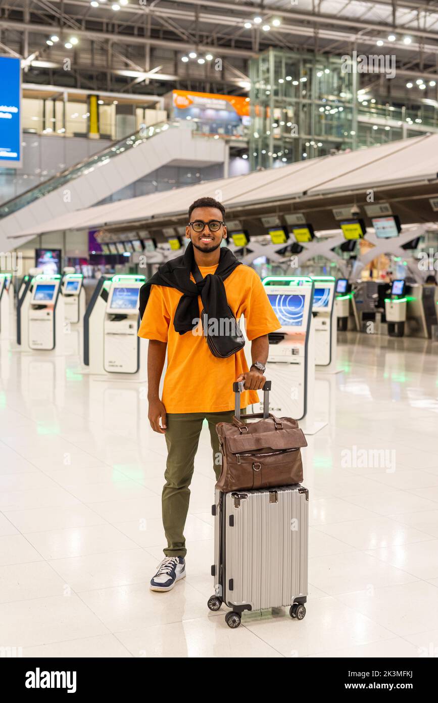 Jeune homme noir élégant prêt à voyager au terminal de l'aéroport en attendant le vol Banque D'Images