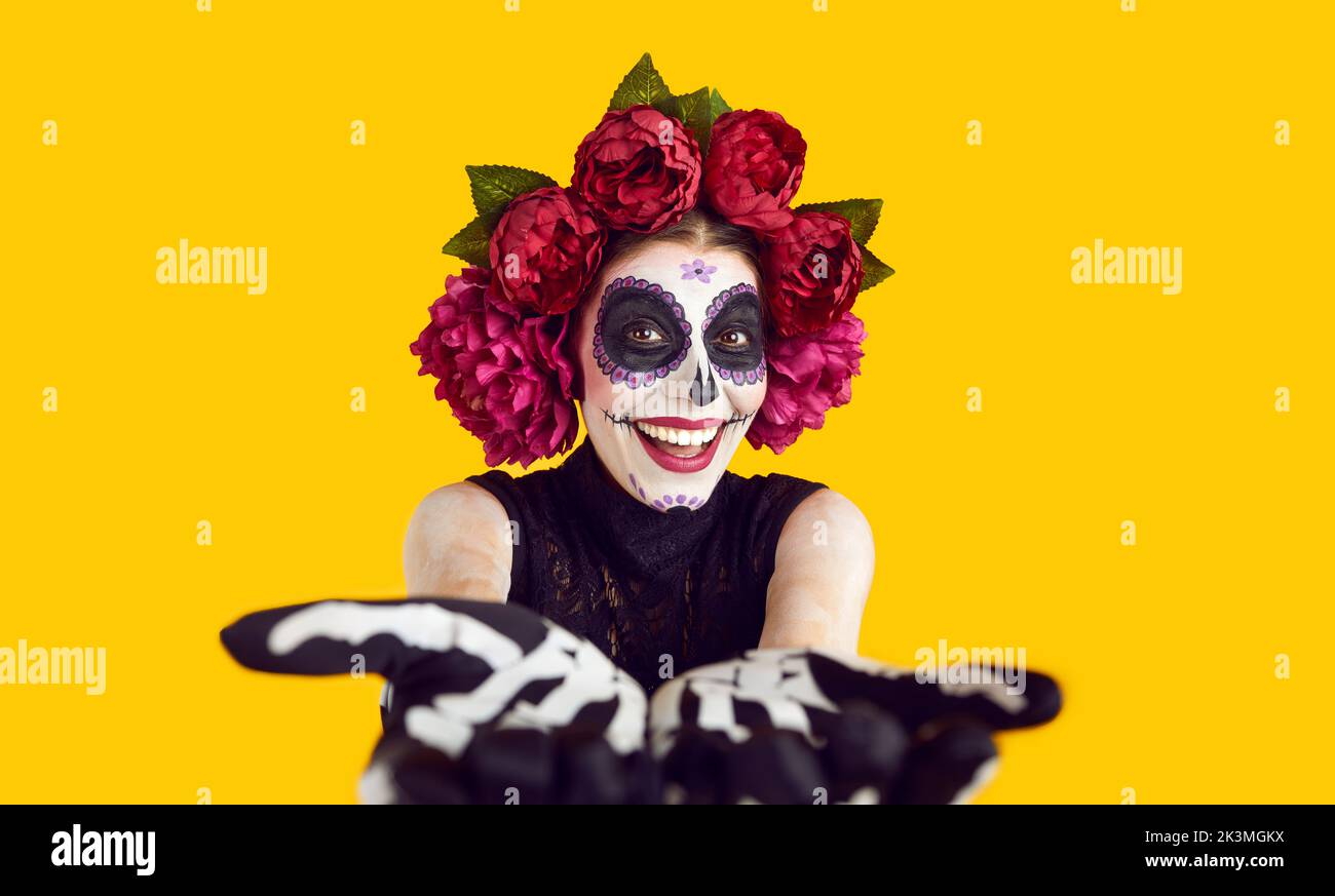 Une femme heureuse vêtue pour Halloween ou le jour des morts souriant et se portant les mains à l'appareil photo Banque D'Images