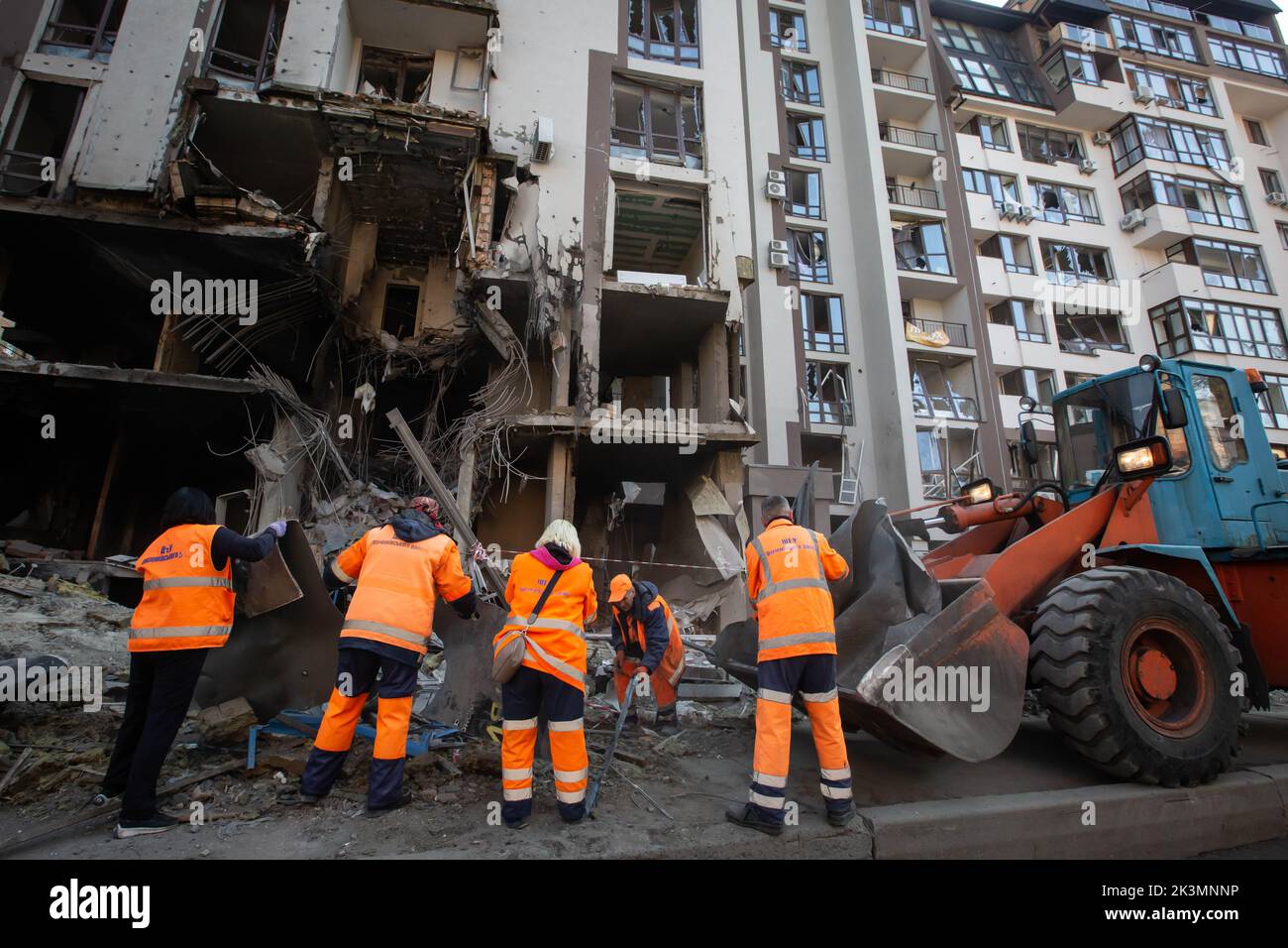 Des travailleurs communautaires nettoient une zone autour d'un immeuble d'appartements détruit lors d'une grève militaire au cours de l'invasion de l'Ukraine par la Russie à Kiev. Banque D'Images