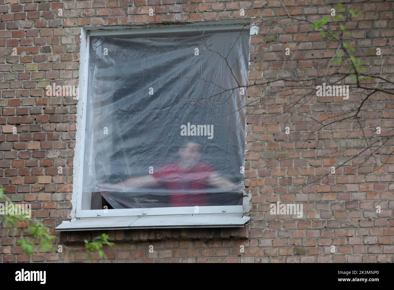 Un homme a vu fermer une fenêtre avec un emballage en plastique dans un immeuble détruit lors d'une grève militaire au milieu de l'invasion de l'Ukraine par la Russie à Kiev. Banque D'Images