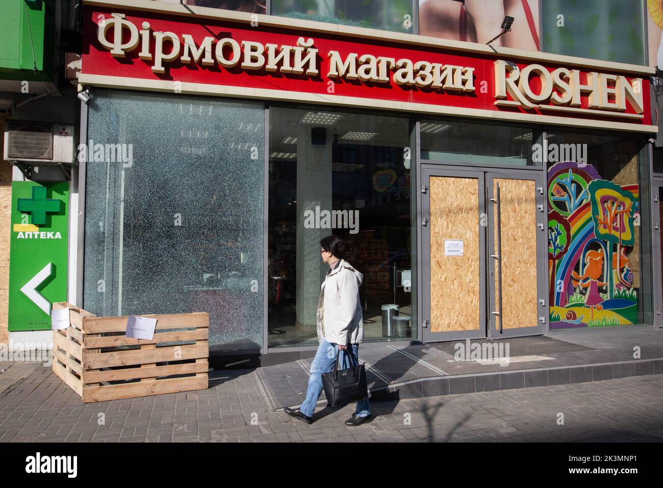 Une femme marche près de la façade d'un magasin de bonbons détruit lors d'une attaque à la roquette au cours de l'invasion de l'Ukraine par la Russie à Kiev. Banque D'Images