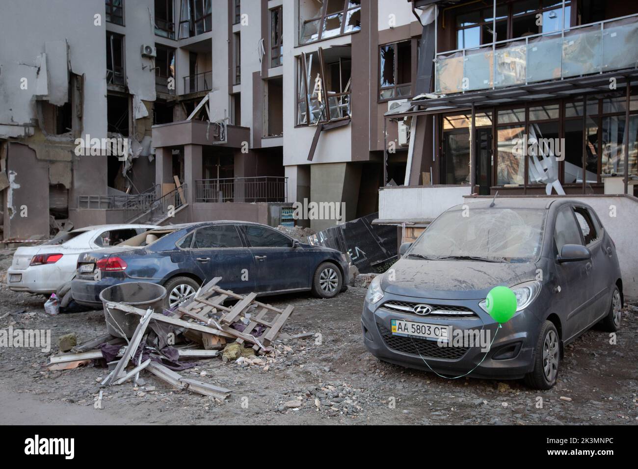 Des voitures garées devant un immeuble d'appartements détruits lors d'une grève militaire au cours de l'invasion de l'Ukraine par la Russie à Kiev. Banque D'Images