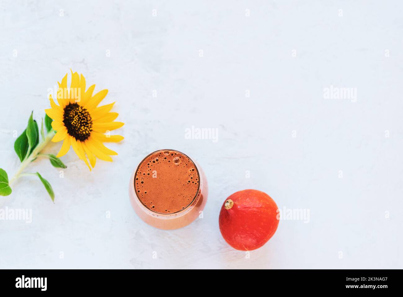 Smoothie de citrouille dans un verre, petit potiron et tournesol sur fond blanc texturé. Vue de dessus, plat, espace de copie. Banque D'Images