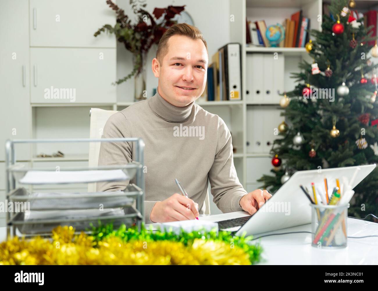 Un homme gai qui fait de la paperasse dans un bureau décoré à Noël Banque D'Images