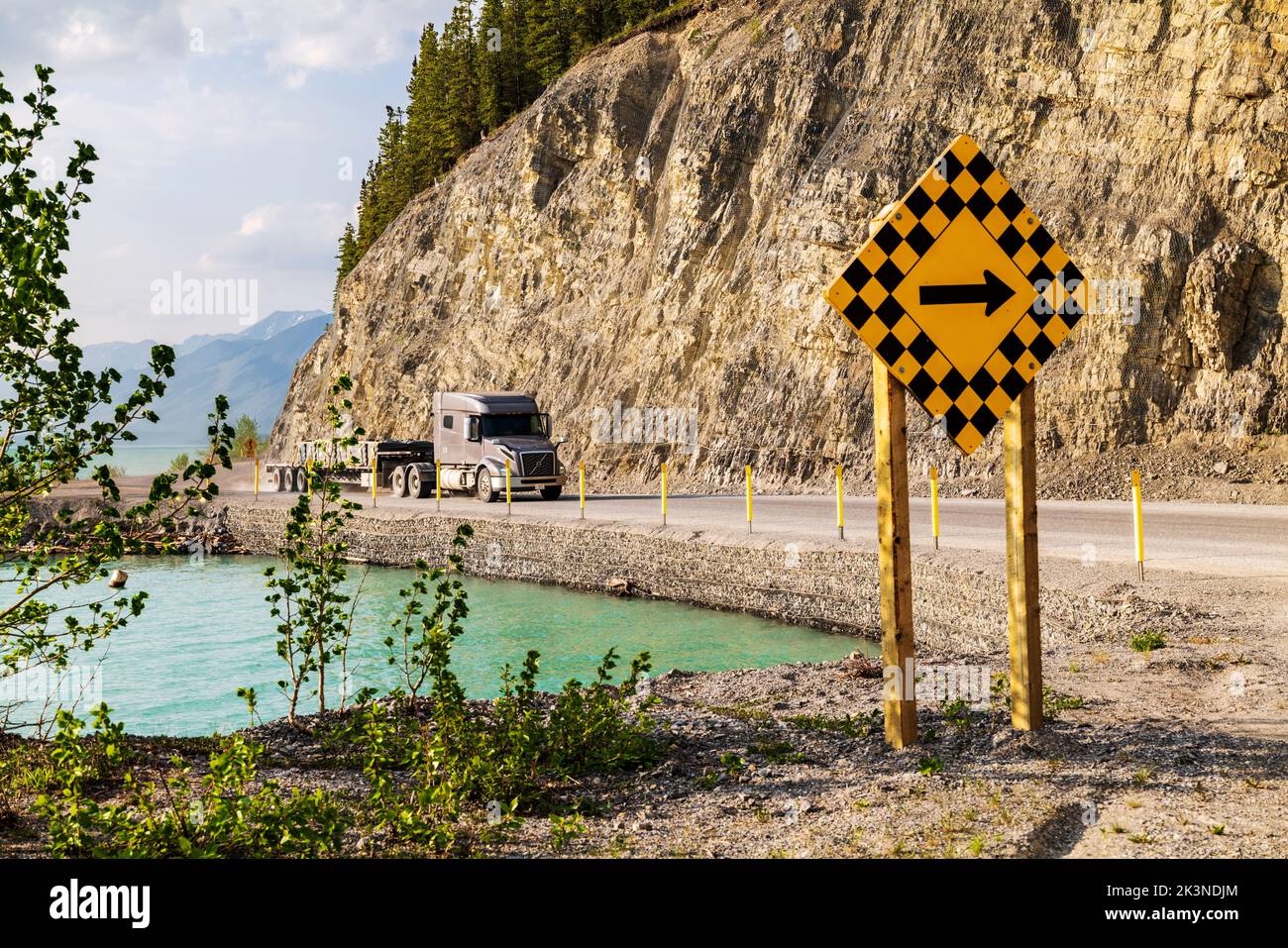 Une remorque-tracteur parcourt la route de l'Alaska le long du lac Muncho, entouré par les montagnes Rocheuses canadiennes, la Colombie-Britannique et le Canada Banque D'Images