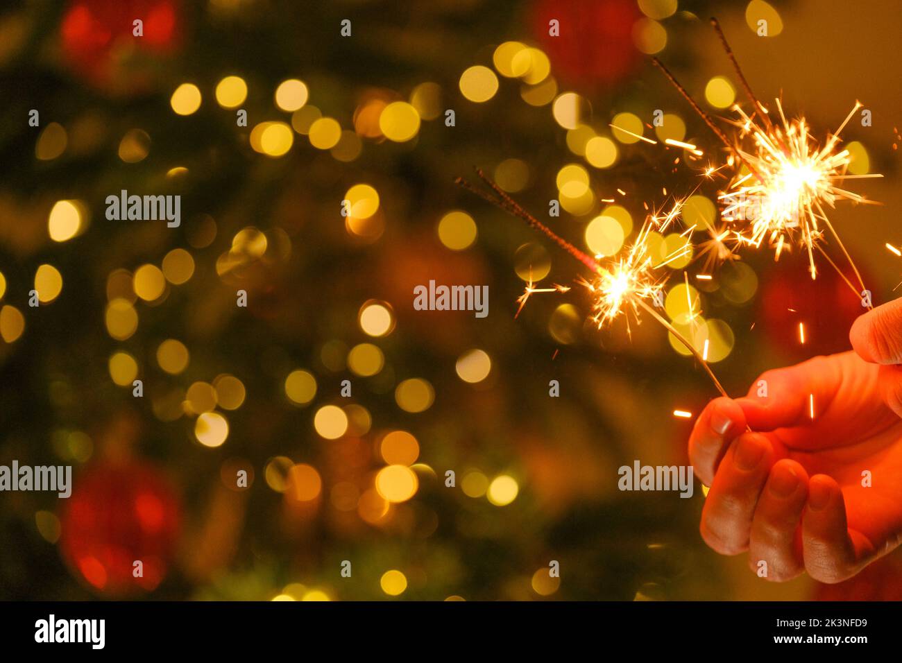 Lumières de Noël et fête du nouvel an. Feu bengale étincelant dans les mains.lumières Bengale sur les guirlandes sur un fond d'arbre de Noël festif Banque D'Images