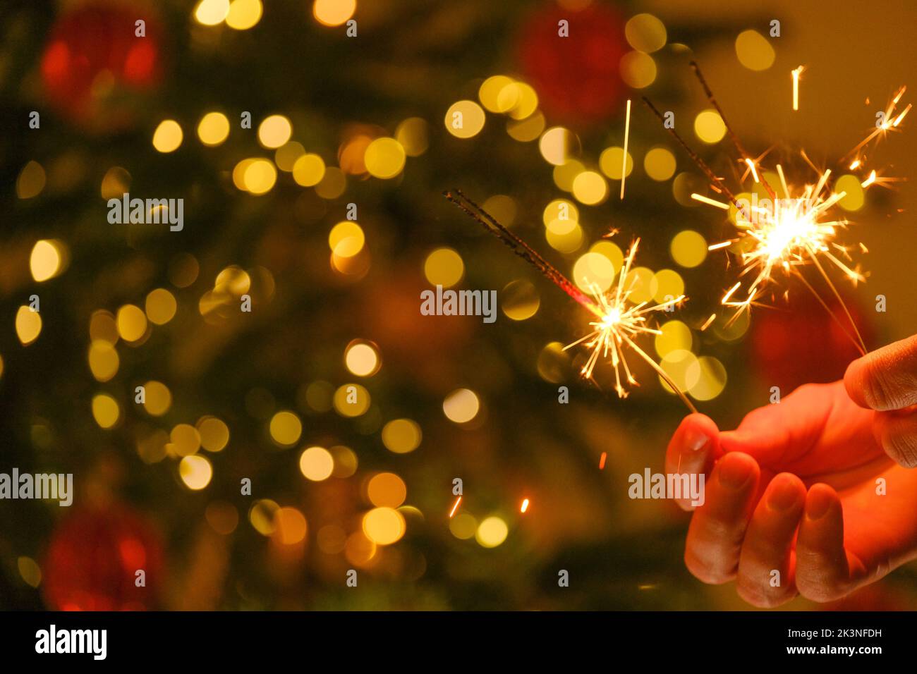 Lumières de Noël et fête du nouvel an. Feu bengale étincelant dans les mains.lumières Bengale sur les guirlandes sur un fond d'arbre de Noël festif Banque D'Images