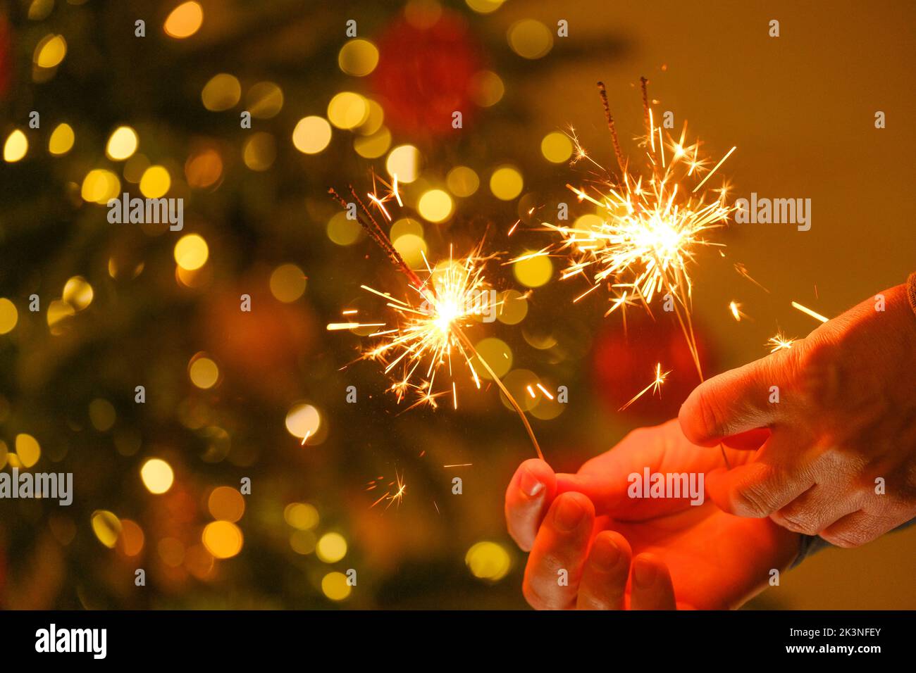 Fête de Noël. Feu bengale étincelant dans les mains.des lumières Bengale sur des guirlandes lumineuses sur un fond d'arbre de Noël festif.Noël brillant Banque D'Images