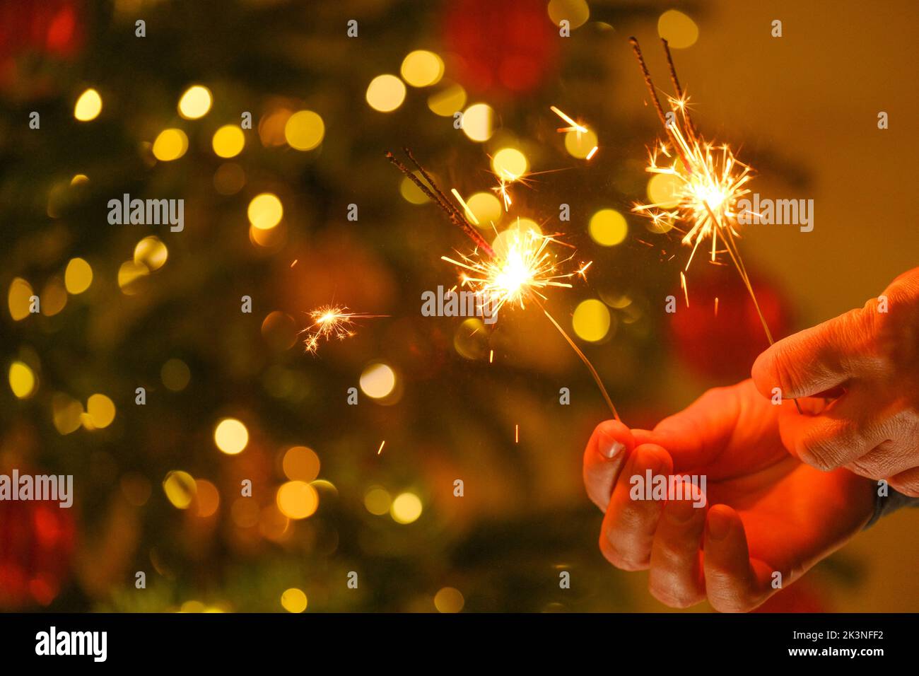 Lumières de Noël et fête du nouvel an. Feu bengale étincelant dans les mains.lumières Bengale sur les guirlandes sur un fond d'arbre de Noël festif Banque D'Images
