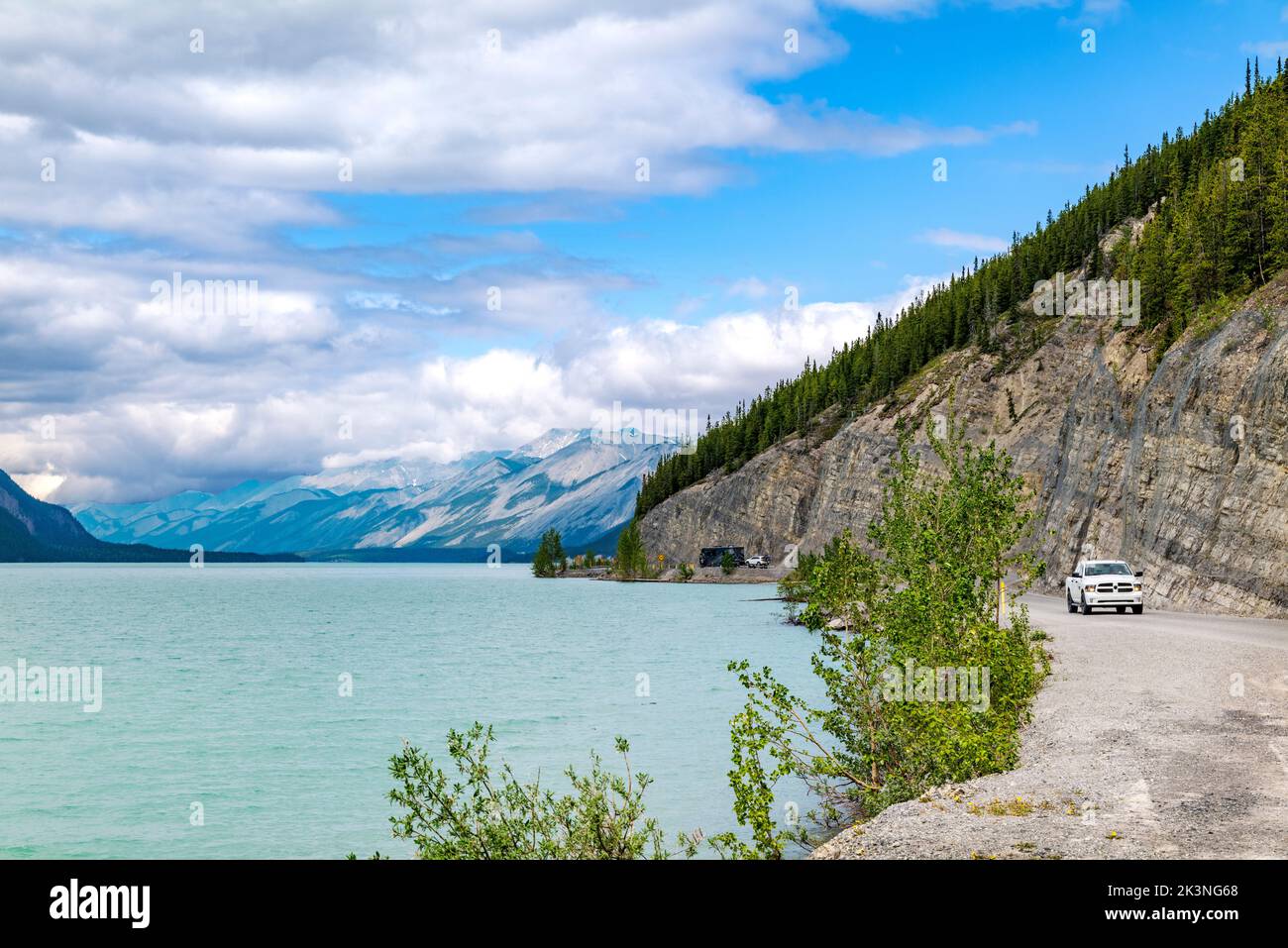 Un camion de ramassage parcourt la route de l'Alaska le long du lac Muncho, entouré par les montagnes Rocheuses canadiennes; la Colombie-Britannique; le Canada Banque D'Images