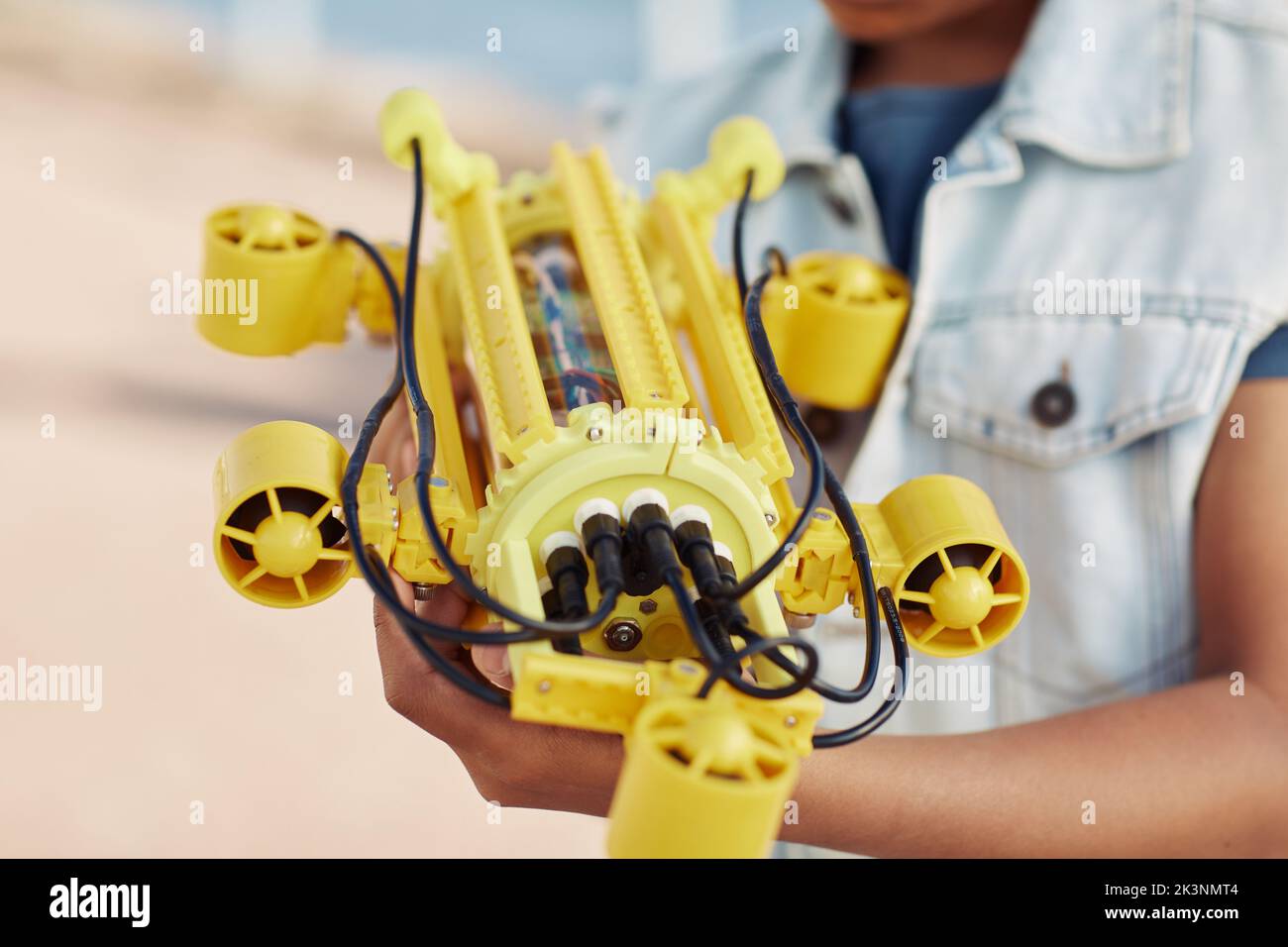 Gros plan d'un enfant méconnaissable tenant un modèle de robot jaune, ingénierie pour l'arrière-plan des enfants Banque D'Images