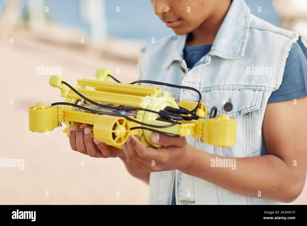 Photo courte d'un jeune garçon noir tenant un modèle robot jaune, ingénierie pour l'arrière-plan des enfants Banque D'Images