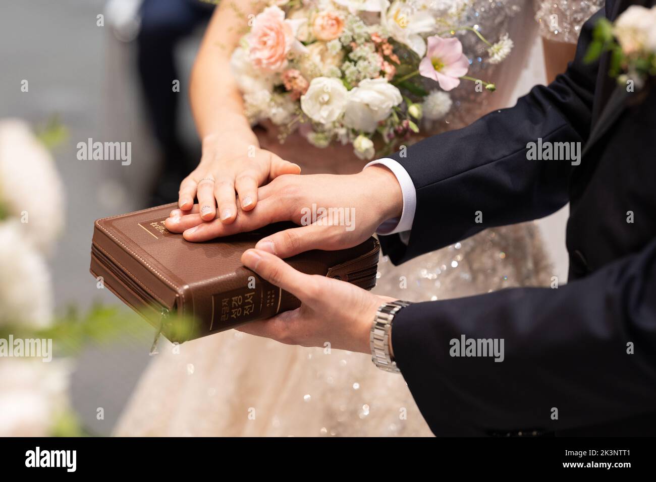Mariée et marié avec des mains sur la bible, cérémonie de mariage dans l'église. Banque D'Images