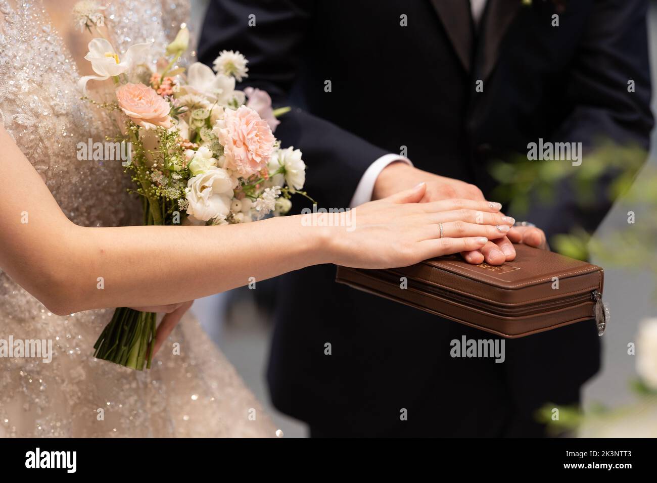 Mariée et marié avec des mains sur la bible, cérémonie de mariage dans l'église. Banque D'Images
