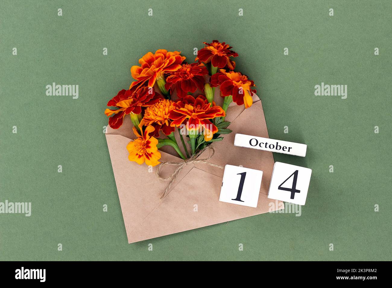14 octobre. Bouquet de fleurs orange en enveloppe artisanale et date calendrier sur fond vert. Concept minimal Hello Fall. Modèle pour votre conception, gr Banque D'Images
