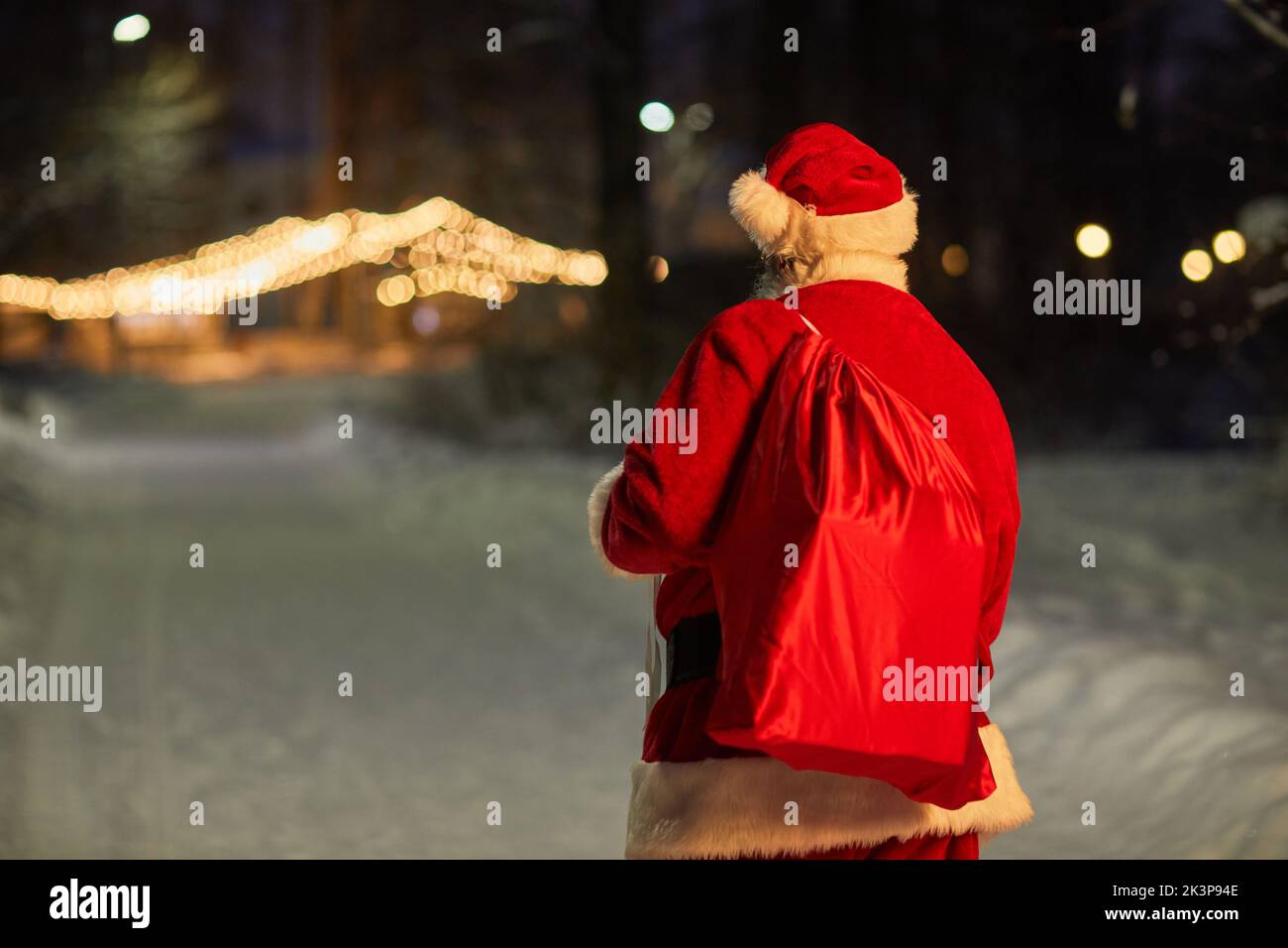 Vue arrière du sac de transport traditionnel du Père Noël avec cadeaux la nuit en ville, espace copie Banque D'Images