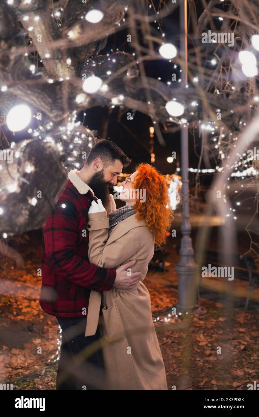 Femme embrassant son mari sous des lumières magiques de Noël Banque D'Images