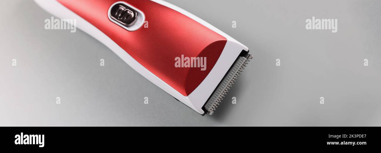 Machine à cheveux électrique pour tondre les cheveux, motif rouge sur surface grise Banque D'Images