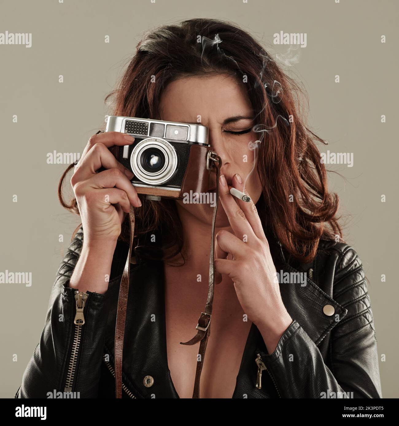 Où sa dépendance et sa passion se rencontrent. Une jeune femme prenant des photos tout en fumant une cigarette. Banque D'Images