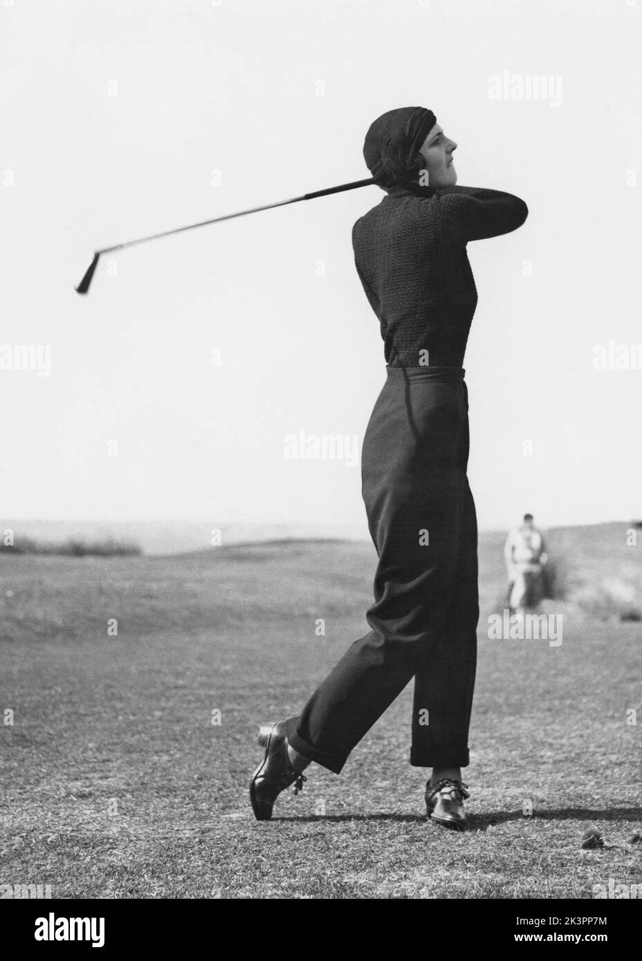 Golf dans le 1930s. Une jeune femme photographiée dans le moment après avoir frappé la balle de golf et cherche à voir si elle est sur le fairway ou pas. Angleterre 1930s Banque D'Images