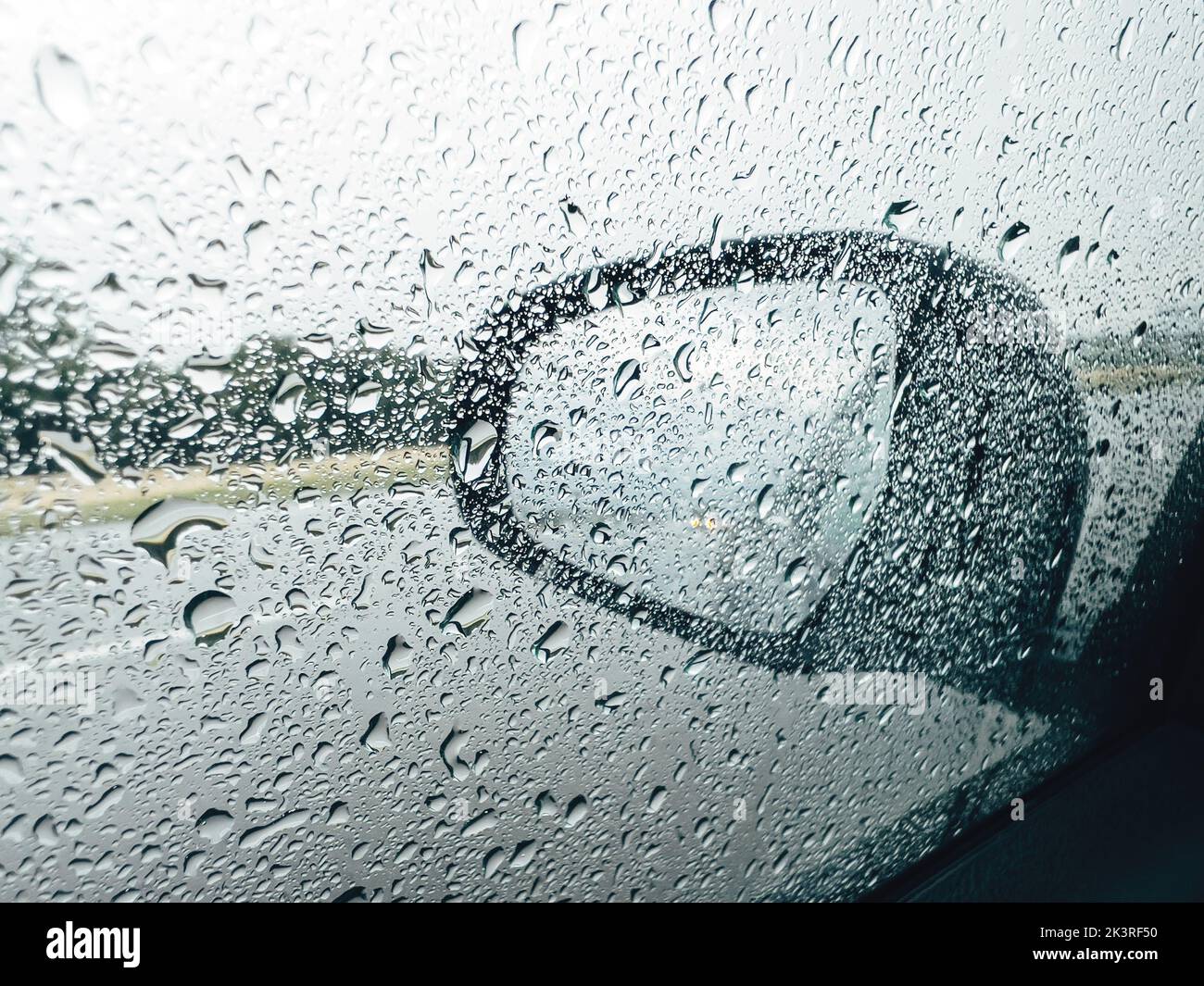 Miroir d'aile de voiture et fenêtre latérale couverte de gouttes de pluie pendant l'été sous la douche tempête de pluie, mise au point sélective Banque D'Images