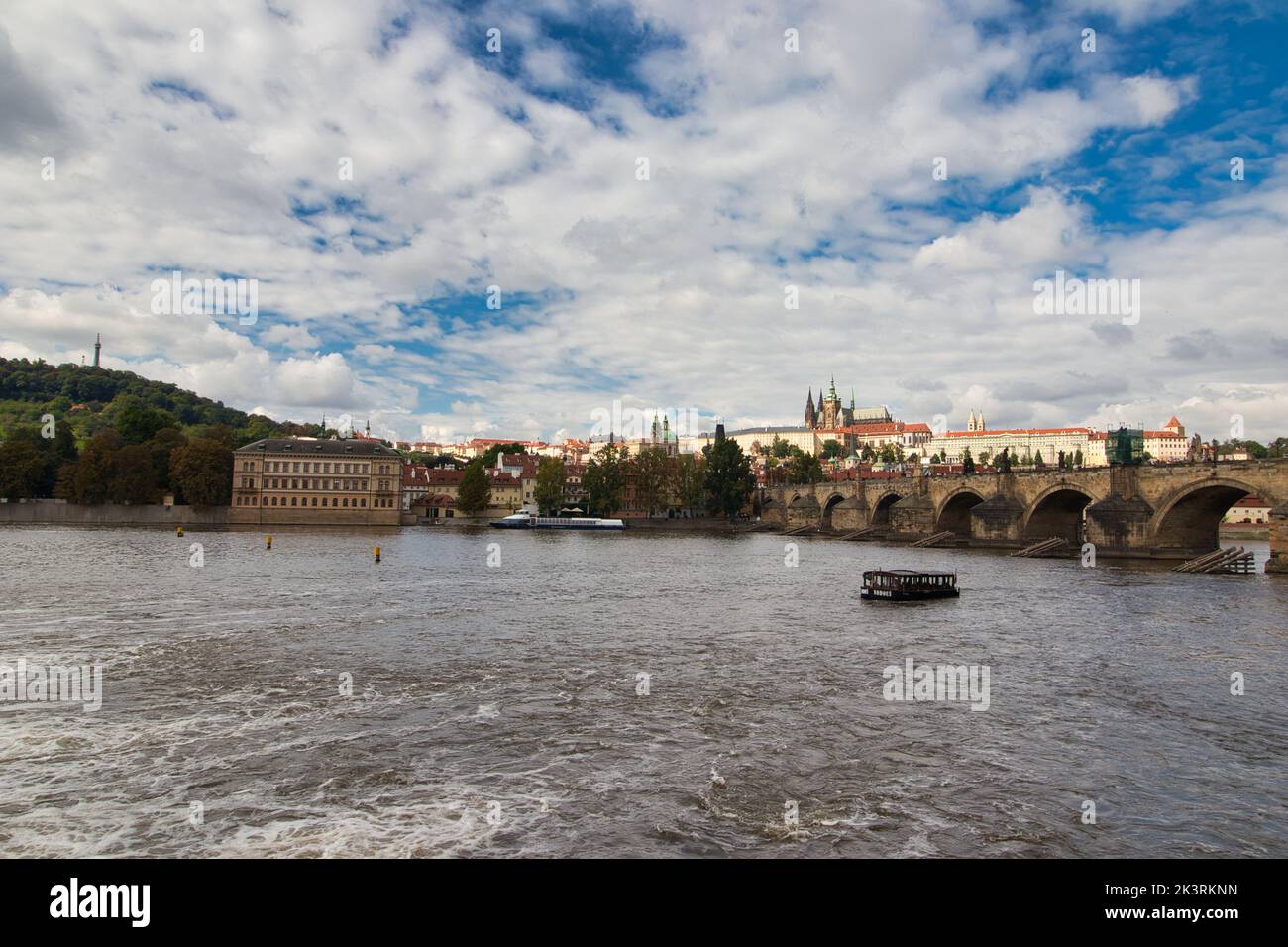 Vue sur la Vltava jusqu'au pont Charles, château de Prague en arrière-plan sous le ciel bleu avec des nuages blancs. Banque D'Images Vue sur la Vltava jusqu'au pont Charles, château de Prague en arrière-plan sous le ciel bleu avec des nuages blancs. Banque D'Images