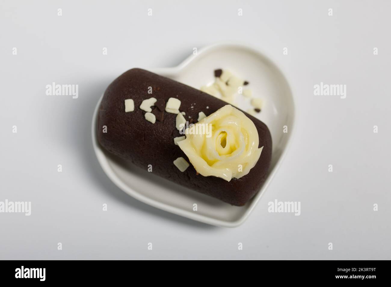 Patate de gâteau sur une soucoupe en forme de coeur. Décoration avec crème au beurre. Sur fond blanc. Gros plan. Banque D'Images