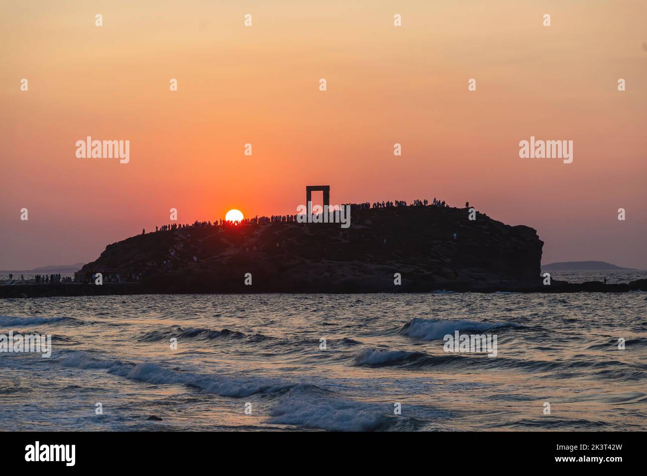 Île de Naxos, coucher de soleil sur le Temple d'Apollon, Cyclades destination Grèce. Les gens admirent le coucher de soleil depuis l'îlot de Palatia. Mer ondulée ciel coloré Banque D'Images
