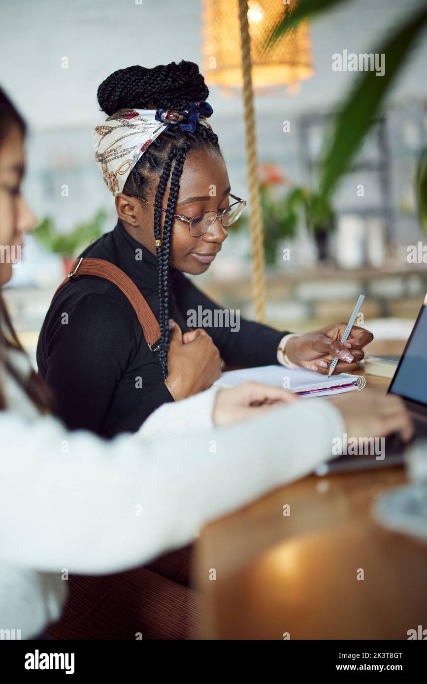 Deux étudiantes multiculturelles s'assoient dans un café et étudient pour l'examen final. Banque D'Images