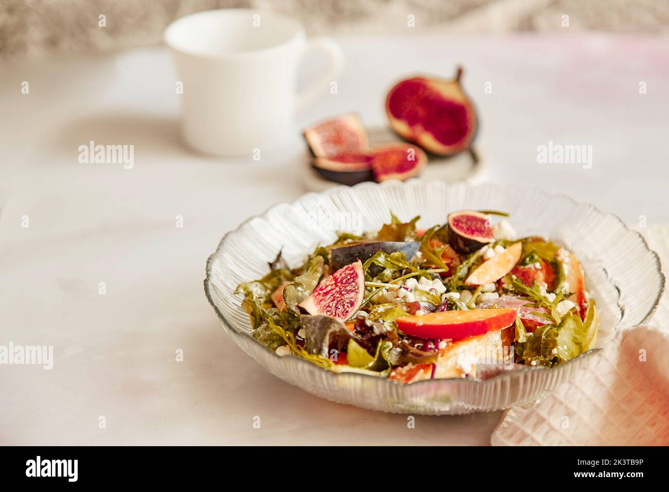 Salade méditerranéenne avec arugula fraîche, fromage à grains, batata et figues, tasse de thé. Petit déjeuner sain, salade végétalienne fraîche. Banque D'Images