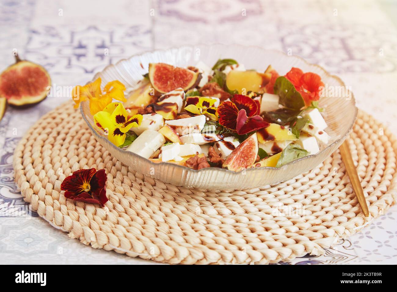 Salade française végétarienne avec féta de mangue, fleurs comestibles, figues, pêche, basilic sur fond de carreaux de céramique. Une alimentation saine. Banque D'Images