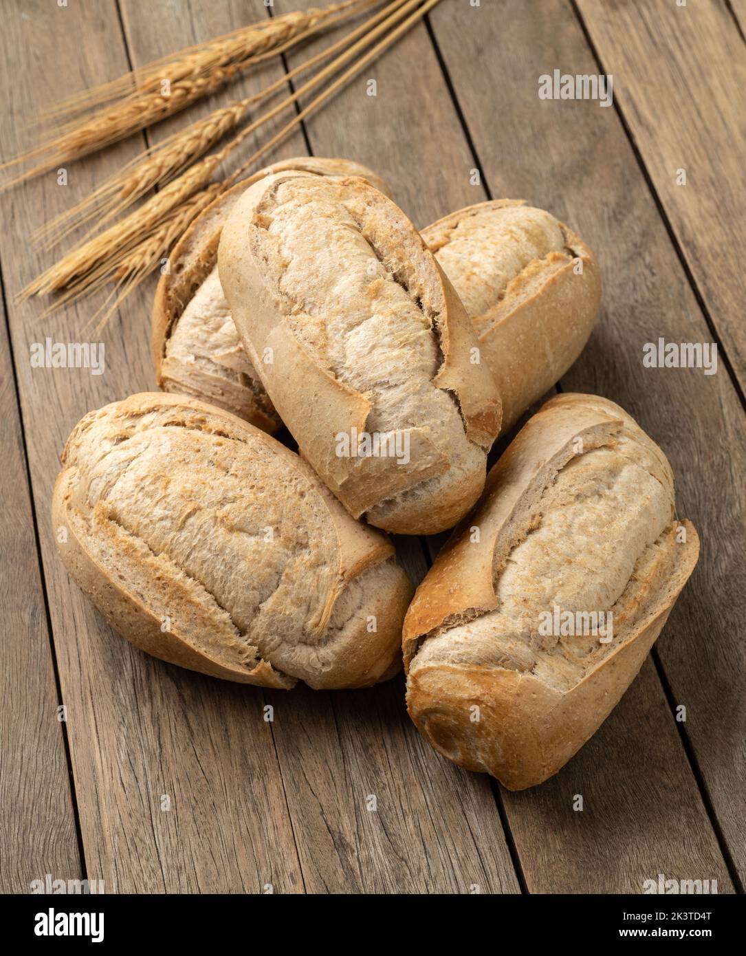 Pain français à grains entiers, pain salé ou pistolet sur table en bois. Banque D'Images